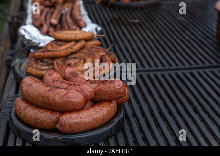 Wurst aus Schweinefleisch und heiße Hunde auf dem Grill, Hot Dogs, Hamburger & Wurstkost auf dem Grill beim Picknickgrill Stockfoto