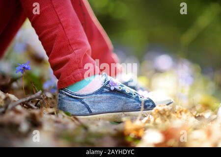 Nahaufnahme von Mädchen Schuhe im Wald an einem schönen sonnigen Frühlingstag. Das Kind pflückt die ersten Blumen des Frühlings im Freien. Kinder erkunden die Natur. Stockfoto