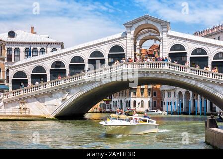 Venedig, Italien - 18. Mai 2017: Wassertaxi fährt unter der Rialtobrücke am Canal Grande in Venedig. Die Rialto-Brücke ist eines der Hauptmerkmale Venedigs. Stockfoto