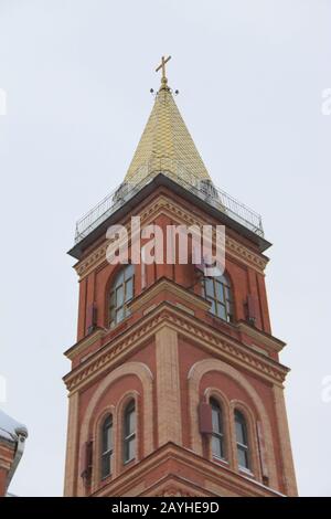 Fragment einer roten Ziegelkirche mit Fenstern und vergoldetem Dach. Stockfoto