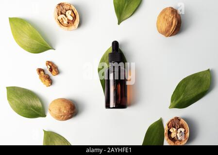 Das Konzept der natürlichen Inhaltsstoffe in der Kosmetik. Kosmetik- und Heilöl aus Nussbaum auf weißem Grund. Natürliche Seren. Flache Lage, Draufsicht. Stockfoto