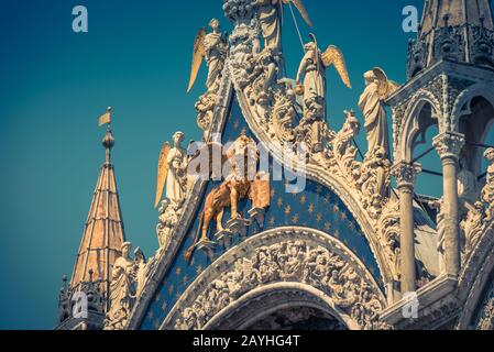 Fassade der Markusbasilika in Venedig, Italien. Der geflügelte Löwe ist ein Symbol Venedigs. Stockfoto