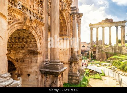 Bogen von Kaiser Septimius Severus und Saturntempel in der Ferne auf dem Forum Romanum in Rom, Italien Stockfoto