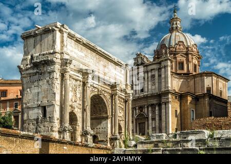 Bogen von Septimius Severus und alte Kirche auf dem Forum Romanum im Sommer, Rom, Italien. Das Forum der Antike ist eines der wichtigsten Wahrzeichen Roms. Vintage-Ansicht des Stockfoto