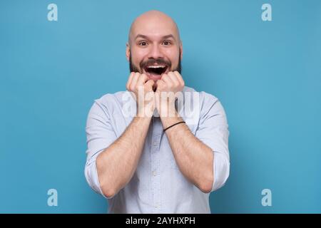 Der glückliche kaukasische bärtige Mann ist begeistert von Neuigkeiten oder Angeboten im tv-Shop. Studio gedreht. Positive menschliche Emotionen im Gesicht. Stockfoto