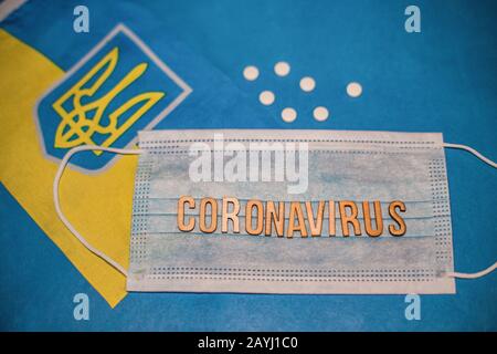 Novel Coronavirus Outbreak-Konzept. Coronavirus Atemschutzmaske und Spritze über verstreute Tabletten und ukrainische Flagge. 2019 nCoV Virus infec Stockfoto