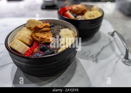 Köstliches Gesundes Frühstück mit Köstlichen Superfood vegane Speisen mit Bananen, Erdbeeren, Hafer, Granola, Beeren und Erdnussbutter Stockfoto