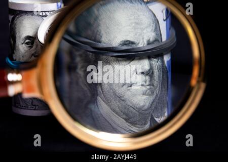 Einhundert Dollar-Scheine unter einer Lupe auf schwarzem Hintergrund Stockfoto