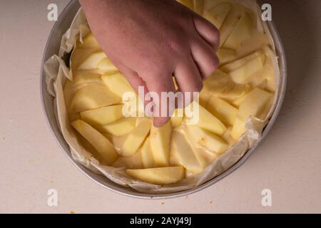 Weibliche Hände legen apfelscheiben vor dem Backen auf einen Kuchen Stockfoto
