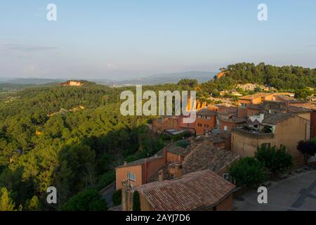Blick auf das Dorf Roussillon in der Region Luberon, Region Provence-Alpen-Cote d Azur im Südosten Frankreichs mit den Ockerfarbenen Felsen im Hintergrund. Stockfoto