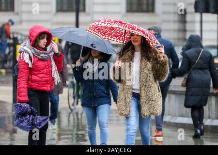 Frauen kämpfen bei nassem und windigem Wetter mit Regenschirmen im Zentrum Londons.Sturm Dennis wird am Wochenende starken Regen und starken Wind über Großbritannien bringen. Stockfoto