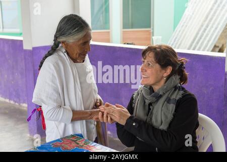 Eine ältere Mixtec-Frau spricht mit einem Touristen im mixtekischen Dorf San Juan Contreras in der Nähe von Oaxaca, Mexiko. Stockfoto