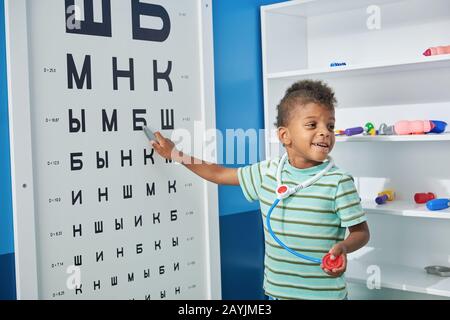 Süßer kleiner Arzt, der Augenuntersuchung unterzogen wird. Stockfoto