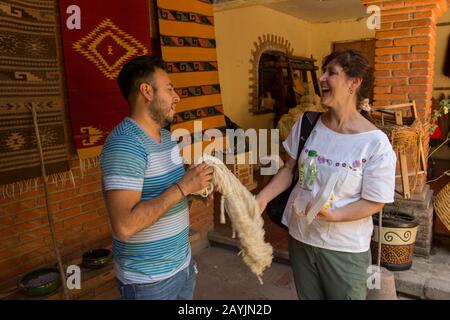 Touristen, die mit einem Weber in seinem Haus in Teotitlan del Valle sprechen, einer Kleinstadt in der Region Valles Centrales in der Nähe von Oaxaca, Südmexiko. Stockfoto