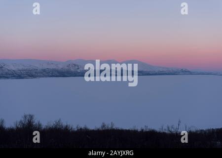 Blick vom Hotel Fjallet auf den gefrorenen und schneebedeckten Tornetrasksee im schwedischen Lappland, Nordschweden. Stockfoto