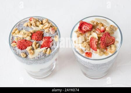 Zwei Gläser chia Seed Pudding mit Mandelmilch, Joghurt, hausgemachtem Granola, getrockneten Erdbeeren und Mandeln. Superfood und veganes Essen Stockfoto