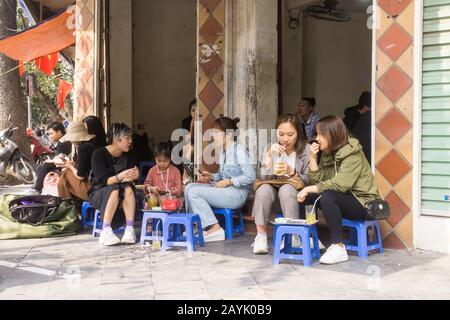 Vietnam-Café - junge vietnamesische Frauen, die in einem Café im alten Viertel in Hanoi auf Plastikhocker sitzen. Südostasiens. Stockfoto