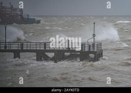 Mann, der am Victoria Pier, Old Portsmouth, Großbritannien, während des Sturms Dennis am Nachmittag des 15. Februar 2020 steht. Stockfoto