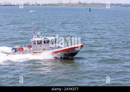 New York, NY USA - 30. Juni 2018: Ein Boot der US-Küstenwache patrouilliert im New Yorker Hafen durch die Freiheitsstatue. Ein bewaffneter Offizier wappnet seine Hand Stockfoto