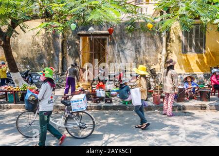 Hoi An, Vietnam - am 1. März 2010: Straßenhändler sitzt unter dem Schatten eines Baumes. Die Sonne ist sehr stark am Nachmittag. Stockfoto