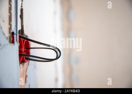 Elektrische Arbeiten mit rauer Oberfläche, Elektriker verbindet und montiert Kupferdrähte für die Steckdose in der Wohnung Stockfoto