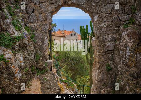 Malerische Aussicht auf die Mittelmeerküste und die mittelalterlichen Häuser durch einen steinernen Torbogen im Dorf Eze, im Süden Frankreichs oder an der französischen Riviera Stockfoto