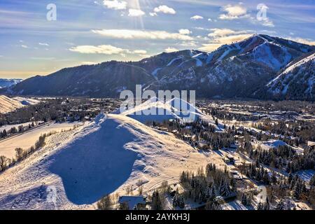 Malerische Winter Mountain Town unter klarem Himmel mit schneebedeckten Gipfeln und Bäumen, Sun Valley, Idaho Stockfoto