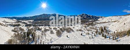 Panorama-Winterlandschaft mit schneebedecktem Gelände und sonnigen Berggipfeln Stockfoto