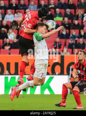 Augsburg, Deutschland. Februar 2020. Florian Niederlechner (C) von Augsburg vies für Kopf mit Robin Koch (TOP) aus Freiburg bei einem Bundesliga-Spiel zwischen dem FC Augsburg und dem SC Freiburg in Augsburg, 15. Februar 2020. Credit: Philippe Ruiz/Xinhua/Alamy Live News Stockfoto