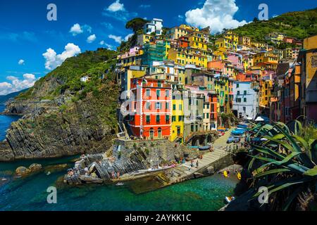 Beeindruckende bunte Gebäude an den Klippen und schöne Bucht mit Touristen im Dorf Riomaggiore, Cinque Terre, Ligurien, Italien, Europa Stockfoto