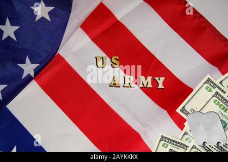 Die Soldaten, die auf Dollarscheinen auf dem US-Flaggenhintergrund mit den Worten US-Armee Militärmarken. Soldatinnen des Vermögens Militärmachtkonzept Stockfoto