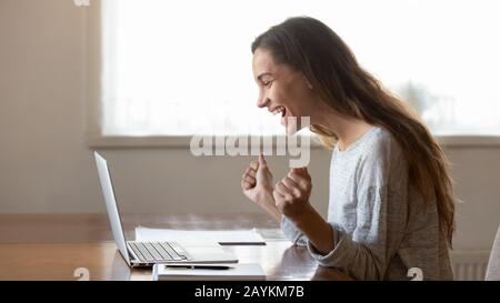 Aufgeregte junge Frau triumphiert beim Lesen guter Nachrichten online Stockfoto