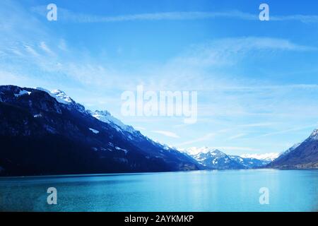 Blaues Meer und Berge mit Schnee auf den Gipfeln. Querformat mit blauer Verlaufsfarbe. Selektiver Fokus. Verschwommener Hintergrund. Stockfoto