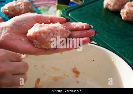 Ein Mädchen mit einer schönen schwarzen Maniküre stellt hausgemachte Häckselchen aus Hackfleisch her. Stockfoto