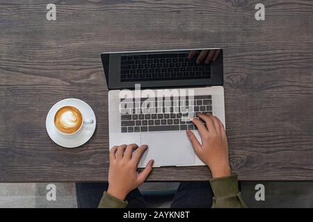 Draufsicht über die junge freiberufliche Handarbeit am Laptop im Coffeeshop Stockfoto