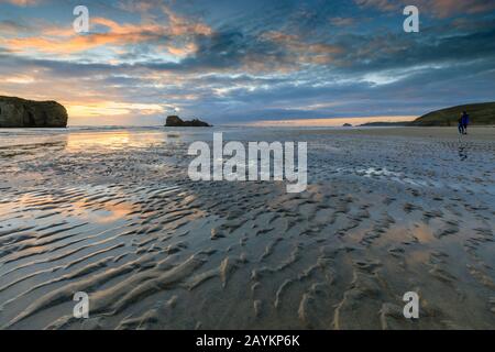 Menschen, die den Sonnenuntergang am Perranporth Beach in Cornwall beobachten. Stockfoto