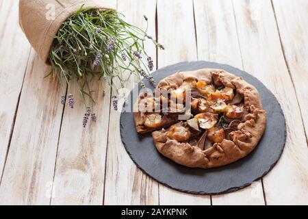 Galette mit Birnen und Käsebrie. Auch bretonische Galette genannt, Galette des Rois, Galeta. Französische Küche. Auf altem weißen Holzhintergrund. Stockfoto