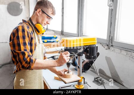 Professioneller Handwerker, der in der Fabrik an Bohrmaschinen arbeitet. Konzept der Technologien und Karriere im Bereich der Handarbeit Stockfoto