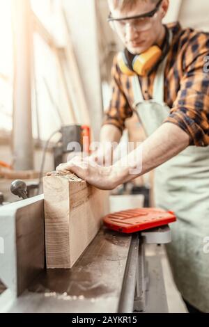 Mann Tischler, der mit Holzwerkstücken an der Baustelle arbeitet. Reparatur- und Arbeitskonzept Stockfoto