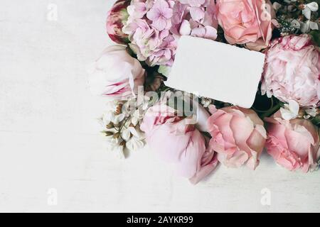 Hochzeit, Geburtstagstiererei Mock-up-Szene. Leere Grußkarte, Einladung. Dekorative Blumenecke aus rosa Rosen, Ponys, Hortensia und Locu Stockfoto