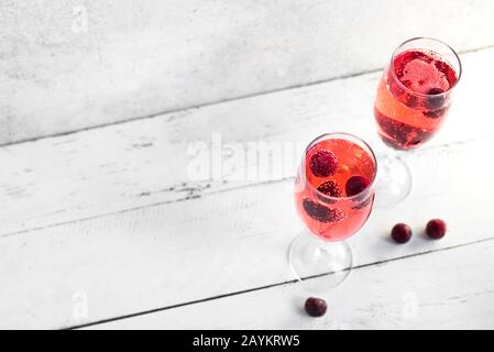 Kir Royal Champagne Cocktail auf weiß, Kopierbereich. Flötenbrille mit Champagnergetränk aus Beere zum Feiern oder Kühlen. Stockfoto