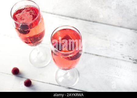 Kir Royal Champagne Cocktail auf weiß, Kopierbereich. Flötenbrille mit Champagnergetränk aus Beere zum Feiern oder Kühlen. Stockfoto