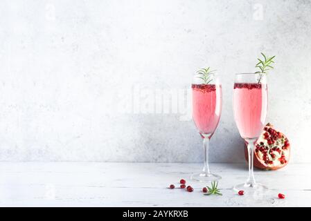 Mimosa-Cocktail mit Rosen-Champagner, Granatapfel und Rosmarin in Flötenbrille, Kopierraum. Mocktail, Mimosa Sekt Rosa Getränk. Stockfoto