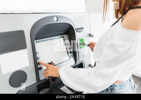 Frau zieht Geld mit Plastikkarte am Geldautomaten ab. Finanz- und Cashflow-Konzept Stockfoto
