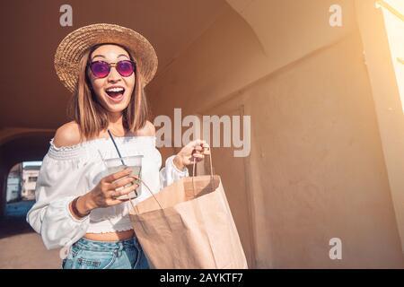 Glückliche asianerin mit Papiertüte nach dem Einkaufen geht spazieren. Lifestyle- und Freizeitkonzept Stockfoto