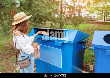 Glückliche asiatin wirft Papier in den Mülleimer. Abfallsortierkonzept Stockfoto