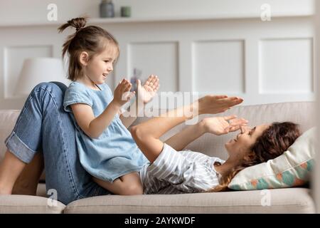 Glückliches kleines Mädchen in der Vorschule, das mit Mama Patty Kuchen spielt. Stockfoto