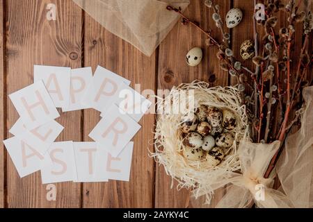 Flache Laienzusammensetzung aus Wachteleiern und Karte mit Text Happy Easter auf Holztisch. Draufsicht. Stockfoto