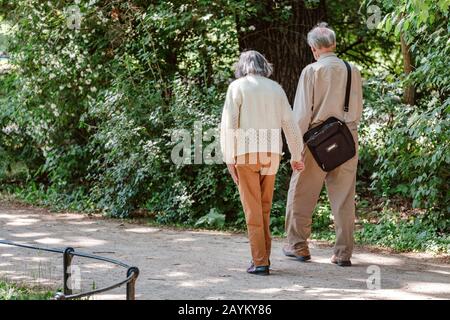 Senioren-Paar, das draußen spazieren geht und Hand in Hand hält Stockfoto