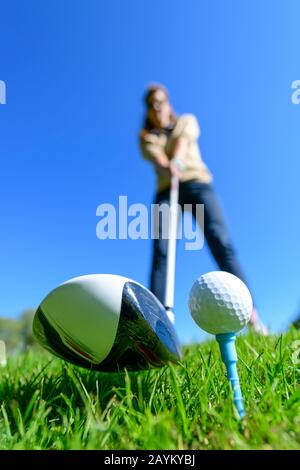 Femaler Golfspieler schlägt mit Fahrer auf einen Ball Stockfoto